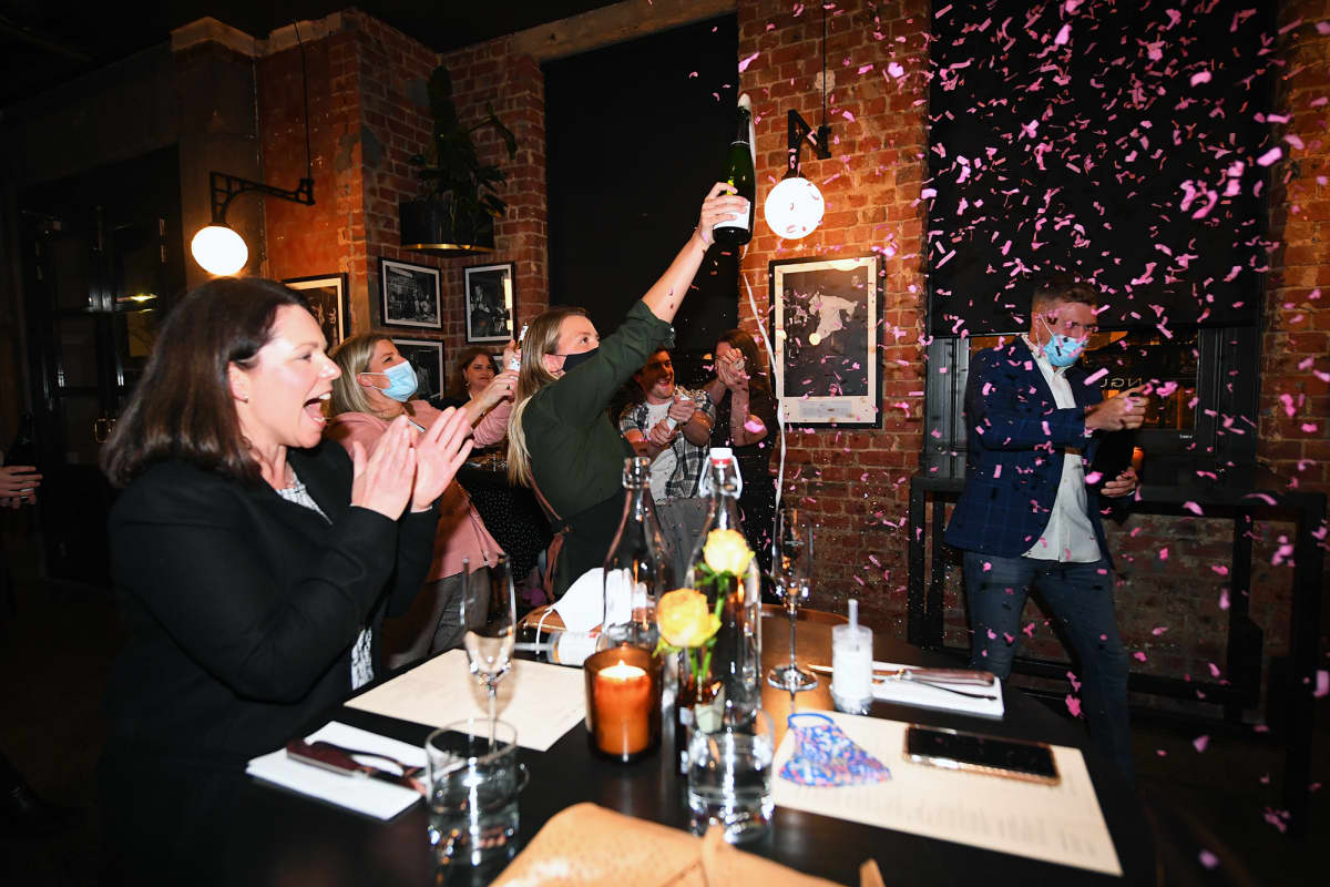 Asiakkaat ja työntekijä juhlivat koronasulun loppumista ruokaravintolassa Melbournessa.