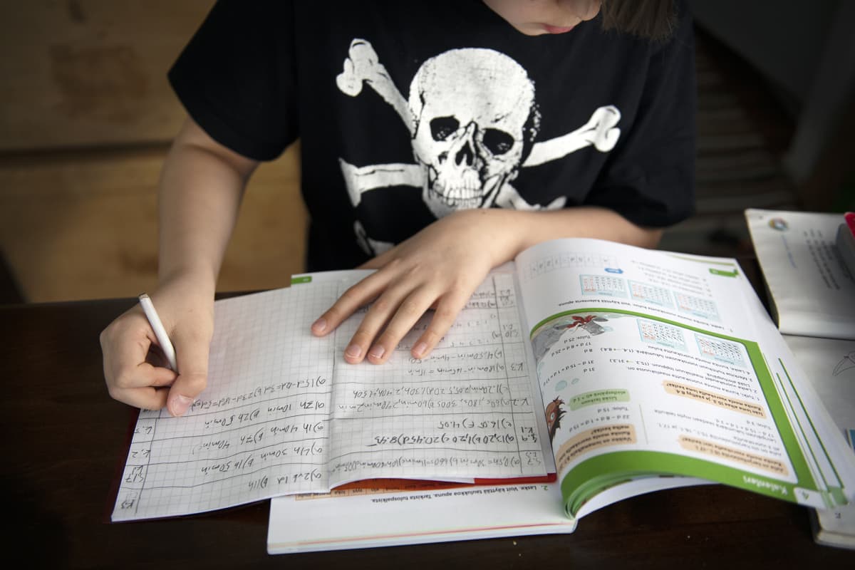 Alakoululainen tekee matematiikan tehtäviä kotonaan.