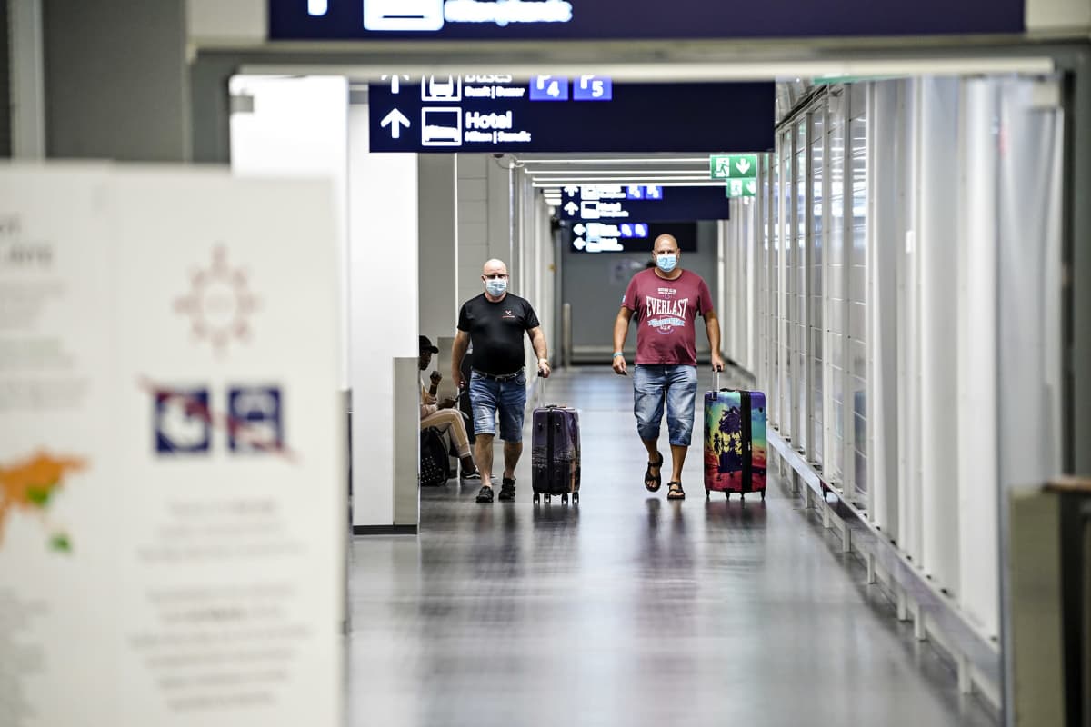 Kaksi matkustajaa kävelee matkatavaroidensa kanssa Helsinki-Vantaan lentoasemalla.
