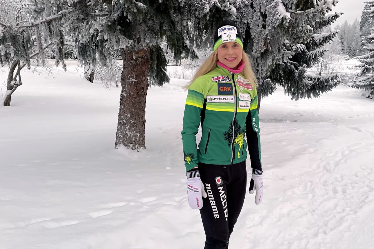Anni Kainulainen seisoo lumisessa maisemassa vihreässä takissa.