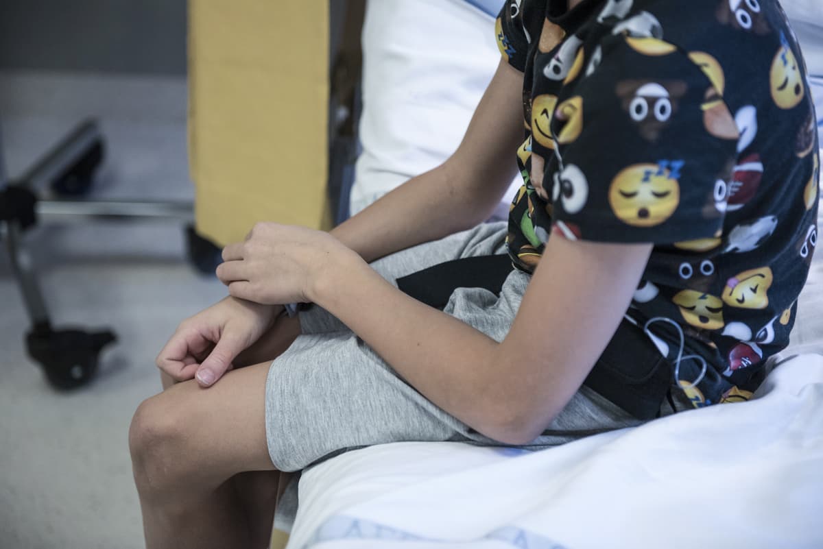Poika istuu sairaalavuoteella.