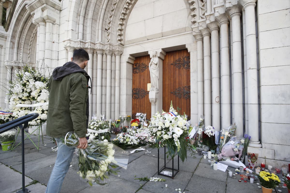Mies laski kukkia Nizzan Notre-Dame-basilikan edustalle 30. lokakuuta 2020. 