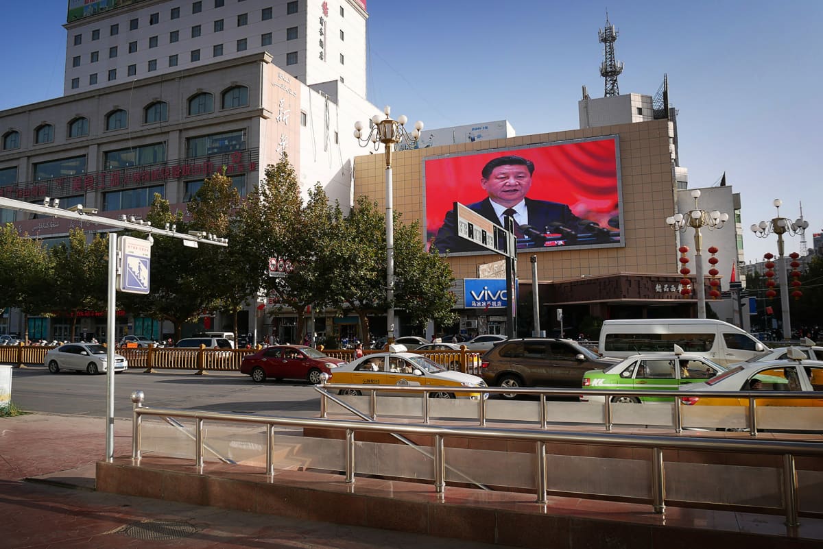 liikennettä, talon seinällä näytössä Kiinan presidentin Xi Jinpingin kuva