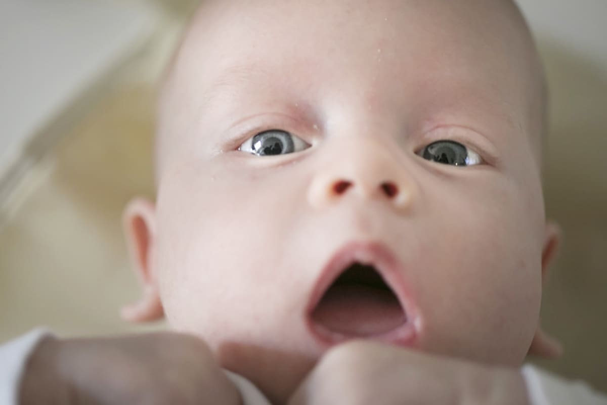 Vauva katsoo kameraan suu auki.