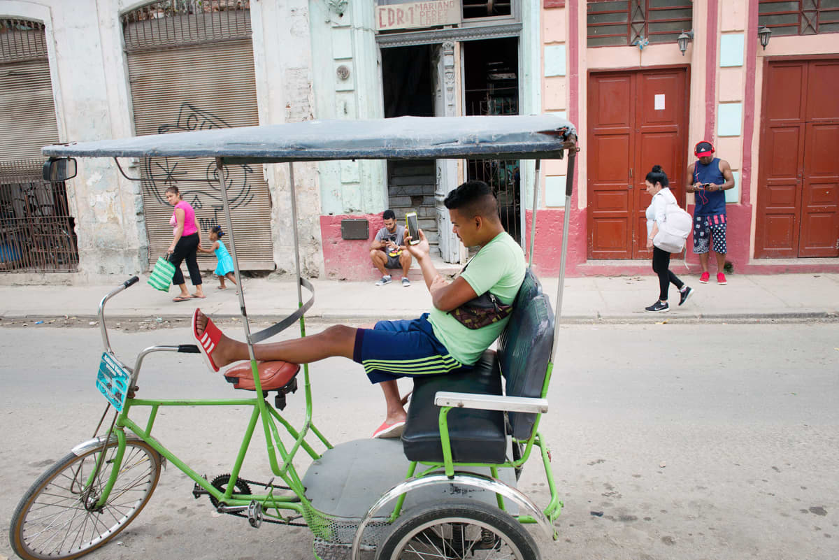 Mies katsoo kännykkäänsä Havannassa.