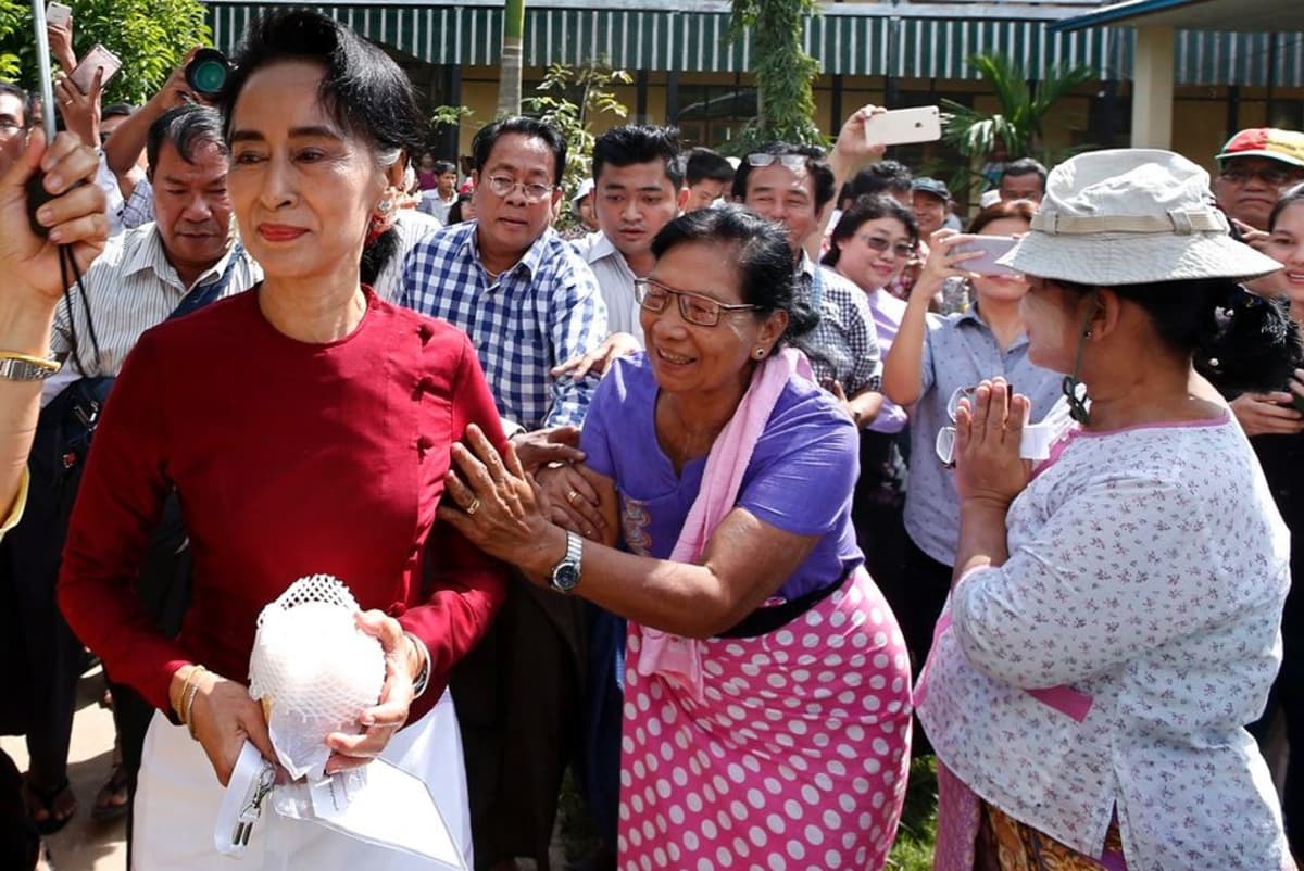 Iloiset ihmiset tervehtivät Aung San Suu Kyita.