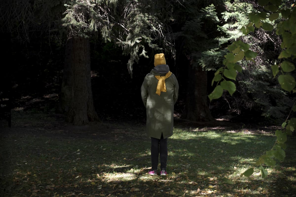 Nainen seisoo metsässä.