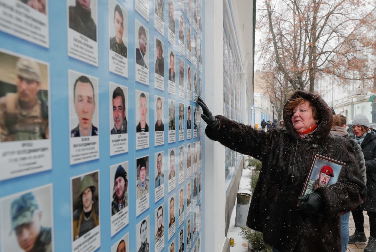 Henkilö katsoo taulua, jossa on sotilaiden kasvokuvia.   ( A woman reacts near the Memory Wall of the Fallen Defenders of Ukraine, who died in the Eastern-Ukrainian conflict, near the St. Mikhail cathedral after a mourning service to honor the 'cyborgs' in Kiev, Ukraine, 21 January 2022. 'Cyborgs' is the collective name of Ukrainian soldiers who defended Donetsk International Airport for 242 days. )