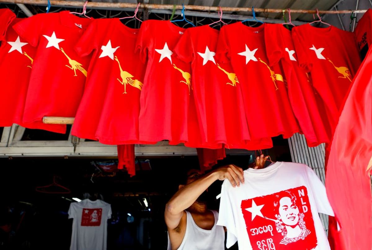 Mies ripustaa NLD-puolueen logolla kuvitettuja paitoja kaupan myyntitelineeseen Yangossa.