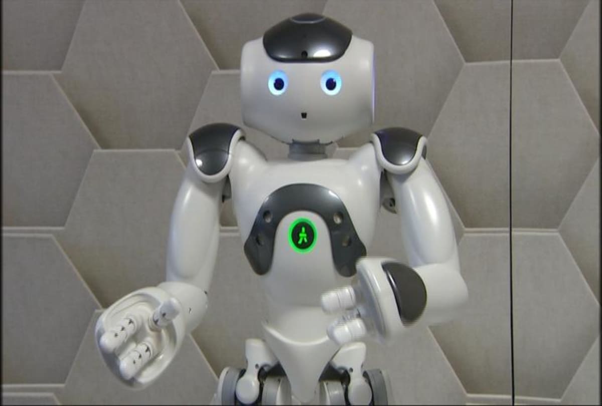 Valko-harmaa Nao robotti seisoo kahdella jalalla ja viittilöi käsillään