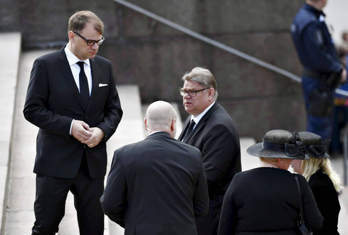 Turvamies seuraa vierestä, kun pääministeri Juha Sipilä ja ulkoministeri Timo Soini saapuvat siunaustilaisuuteen Tuomiokirkkoon presidentti Mauno Koiviston valtiollisissa hautajaisissa Helsingissä 25. toukokuuta 2017.