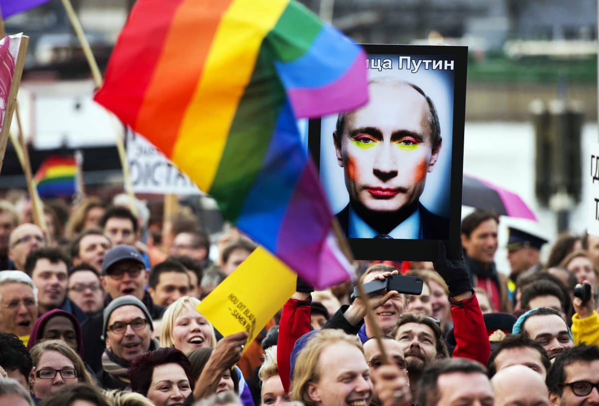 Mielenosoituksessa heilutetaan sateenkaarilipuja ja kannetaan kuvaa, joka esittää vahvasti meikatun Putinin.