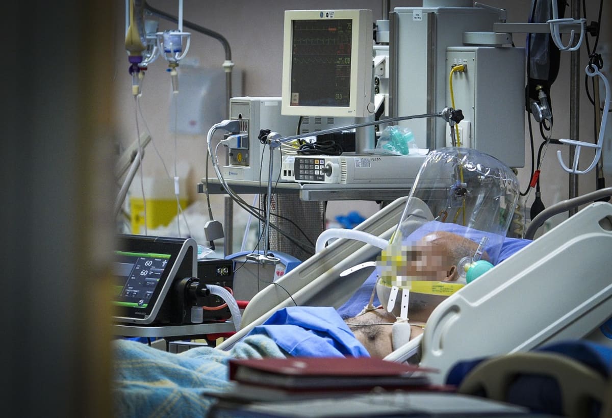 Potilas makaa sairaalavuoteessa hengitysmkoneessa, sängyn ympärillä useita sairaalalaitteita. Kasvot pixelöity. Koronapotilas hengityskoneessa milanolaisessa sairaalassa maaliskuun lopussa.