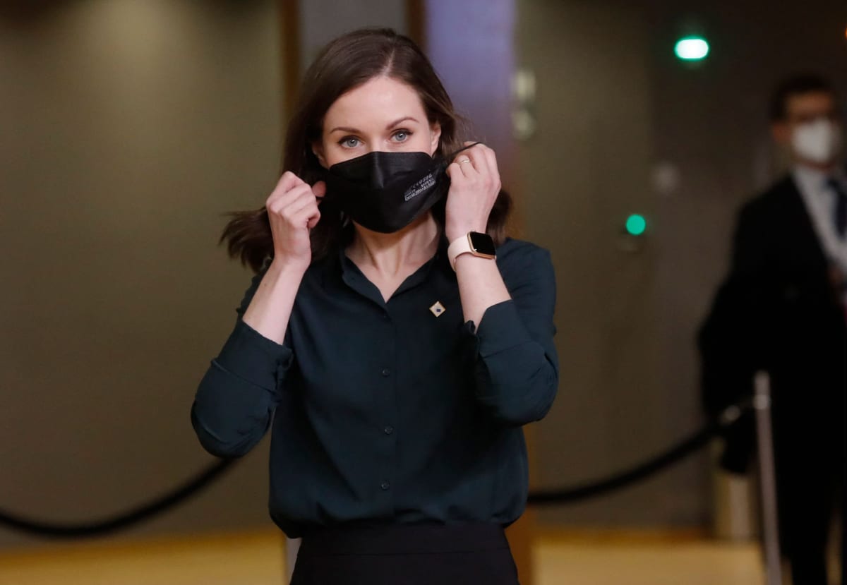 Sanna Marin laittamassa kasvomaskia kasvoilleen.