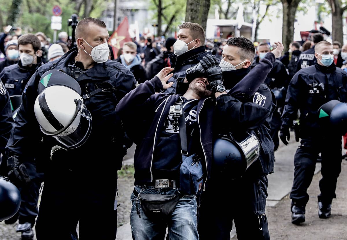 Poliisi kiinniottaa koronarajoituksia vastustavaa mielenosoittajaa.