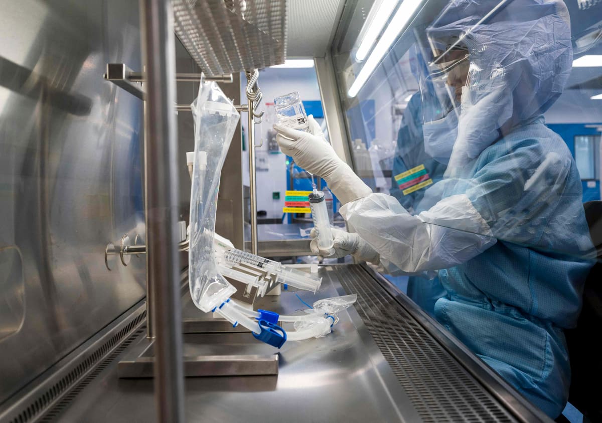 Suojavarusteisiin pukeutunut työntekijä testaa koronarokotteen valmistusmenetelmää laboratoriossa.