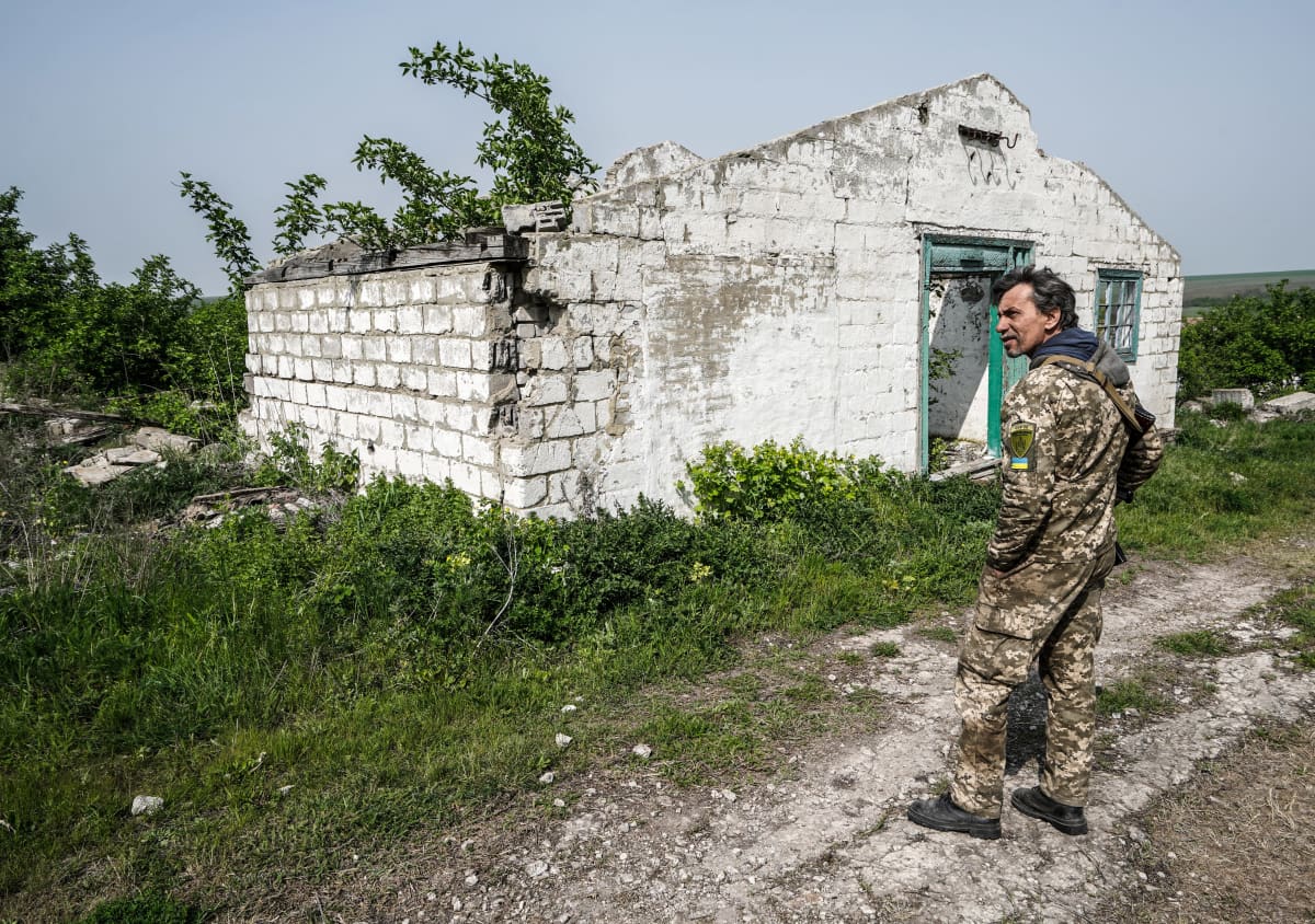 Ukrainalainen sotilas tuhoutuneen talon edessä.