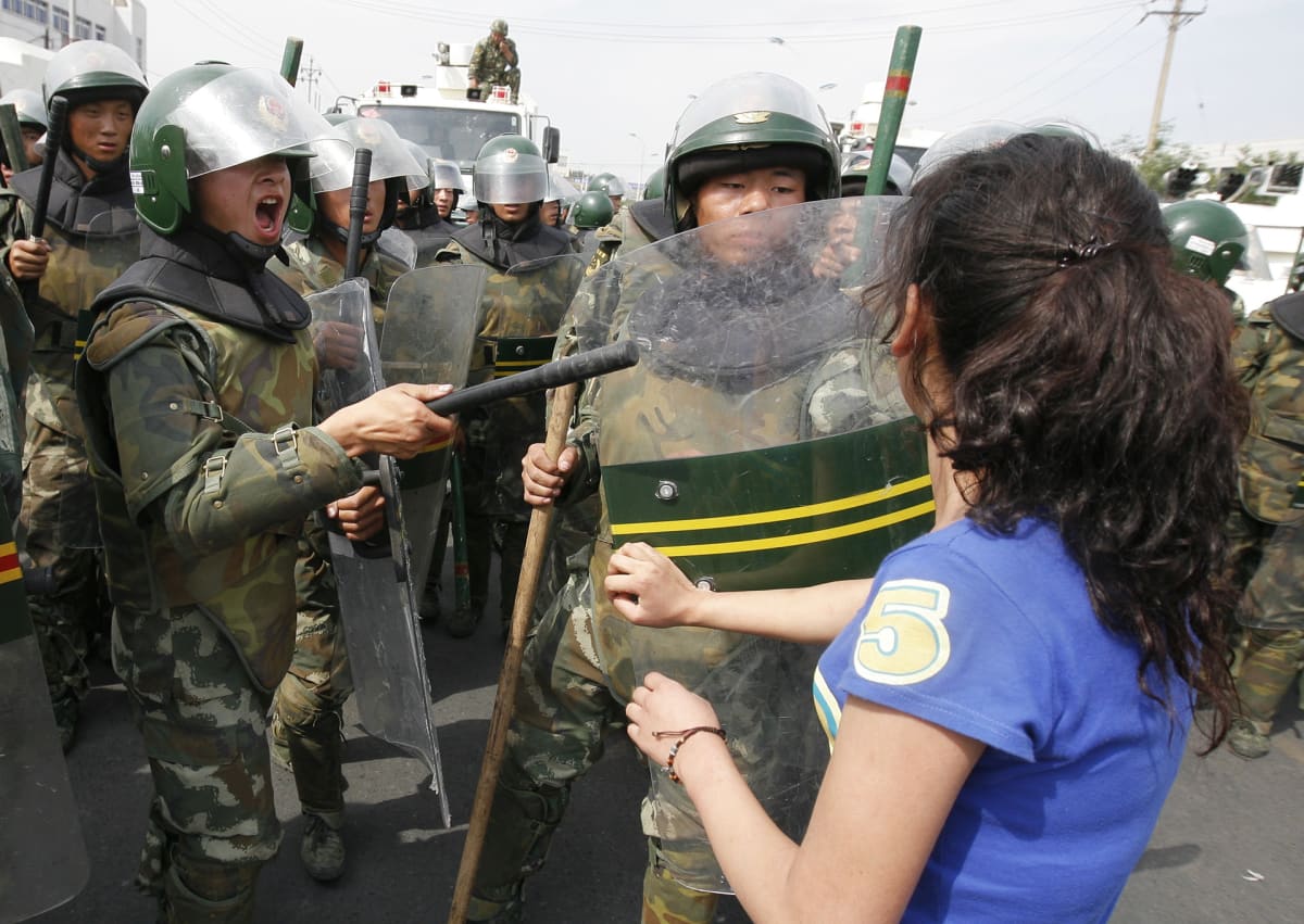 Uiguurinainen ja mellakkapoliiseja.