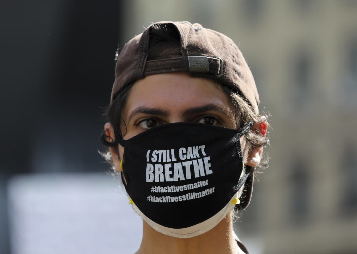 New Yorkissa mielenosoittaja on pukeutunut mustaan kasvomaskiin, jossa lukee "En vieläkään voi hengittää".