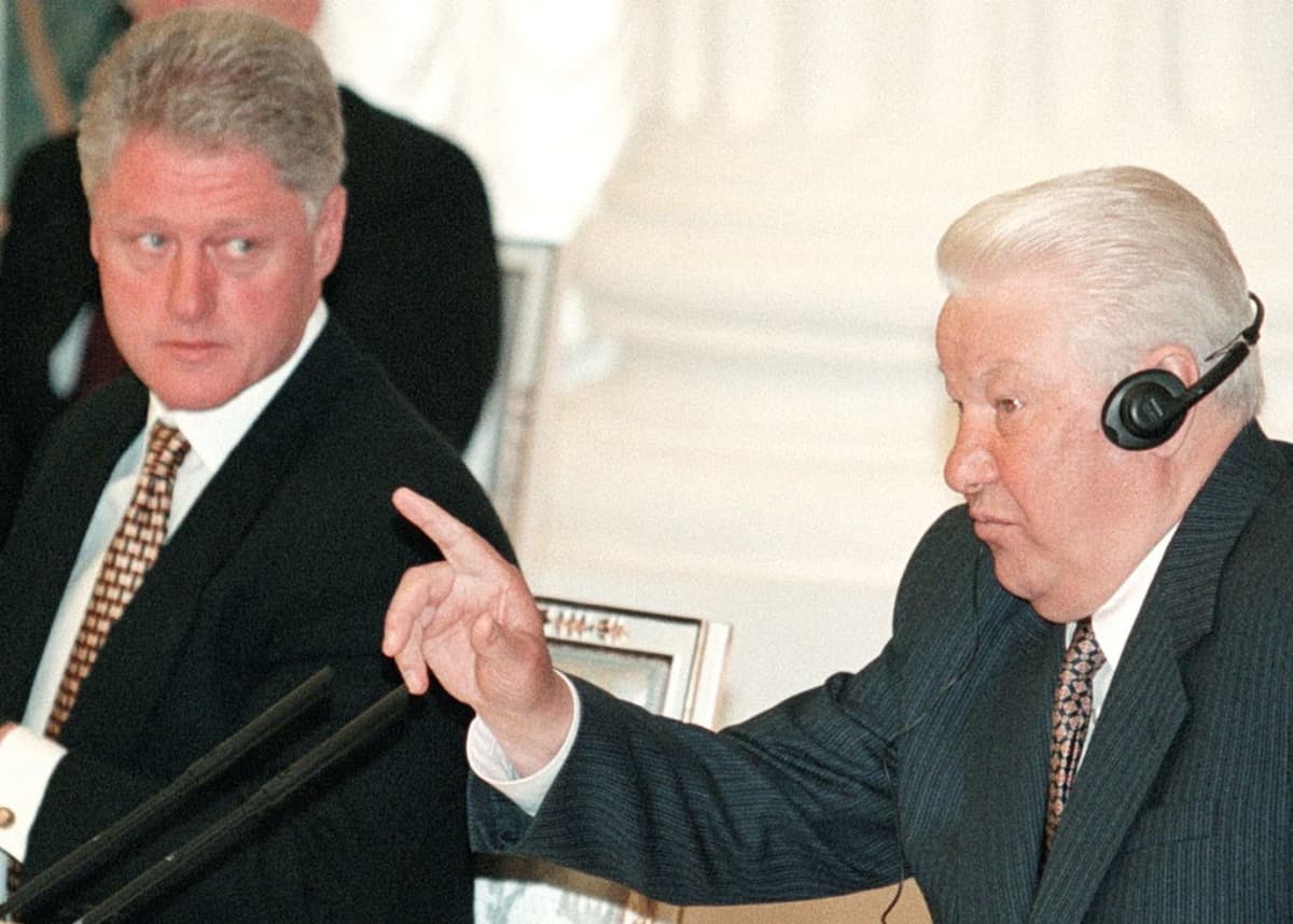 Bill Clinton ja Boris Jeltsin lehdistötilaisuudessa, Jeltsin puhuu käsi pystyssä, Clinton katsoo vieressä. 