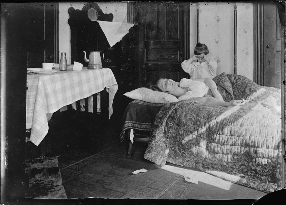 Mustavalkoinen valukuva sängyssä makaavasta naisesta ja vuoreen ääressä itkevästä pikkutytöstä. Influenssan merkki on vain lattialle pudonnut nenäliina.