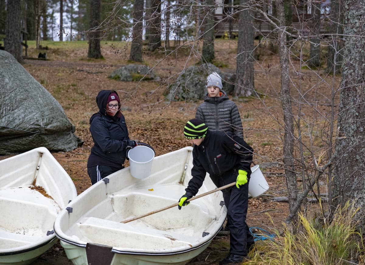 Vili Varonen ja Roope Litmanen pesemässä soutuvenettä yhdessä nuorisotyöntekijä Anni Tahvanaisen kanssa.