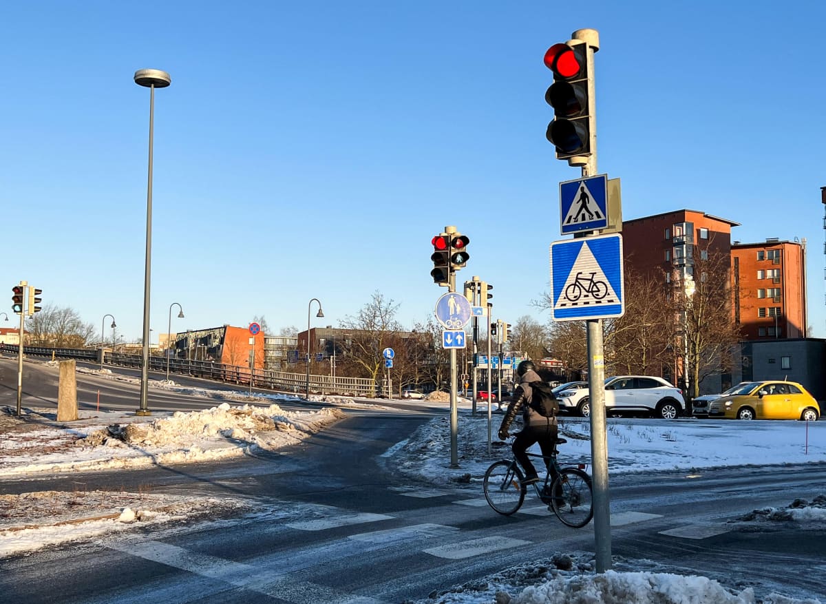 Polkupyöräilijä yrittää suojatietä Turun Aninkaistensillan kupeessa. Liikennemerkki B7, väistämisvelvollisuus pyöräilijän tienylityspaikassa. Neliönmallisessa sinipohjaisessa merkissa on valkoisen kolmion sisällä polkupyörän kuva sekä katkoviivoitus osoittamassa pyörätien jatketta.