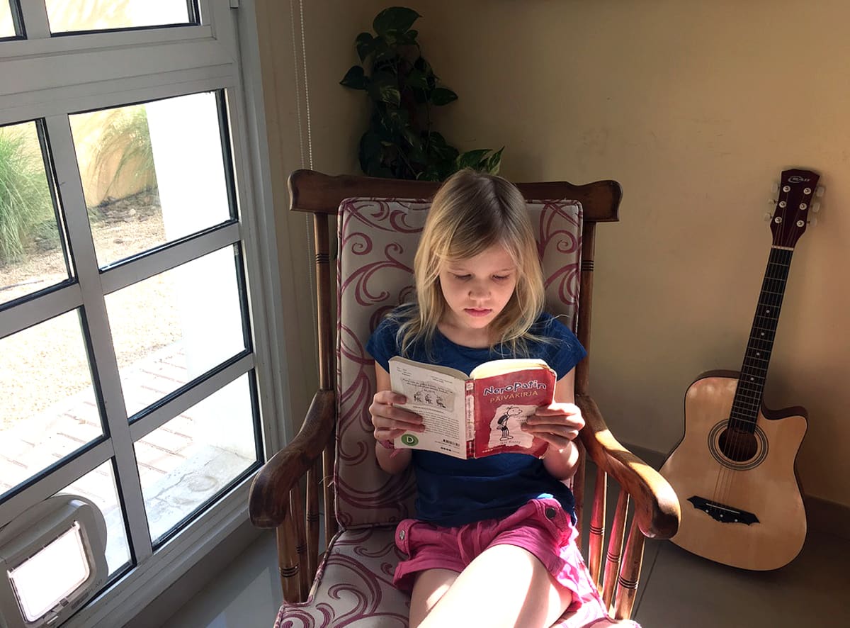 Kuvassa tyttö lukee kirjaa keinutuolissa.