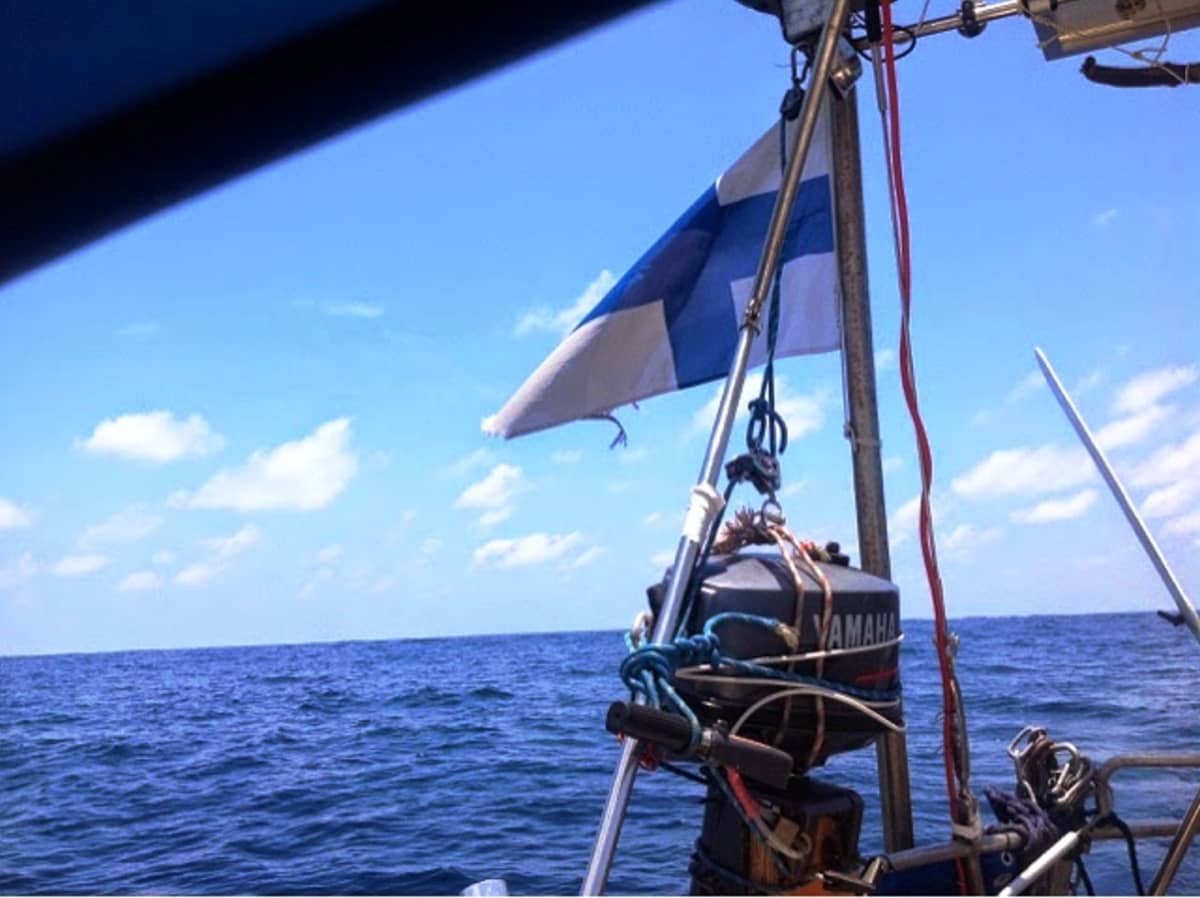 Suomenlippu veneessä ja taustalla aava meri