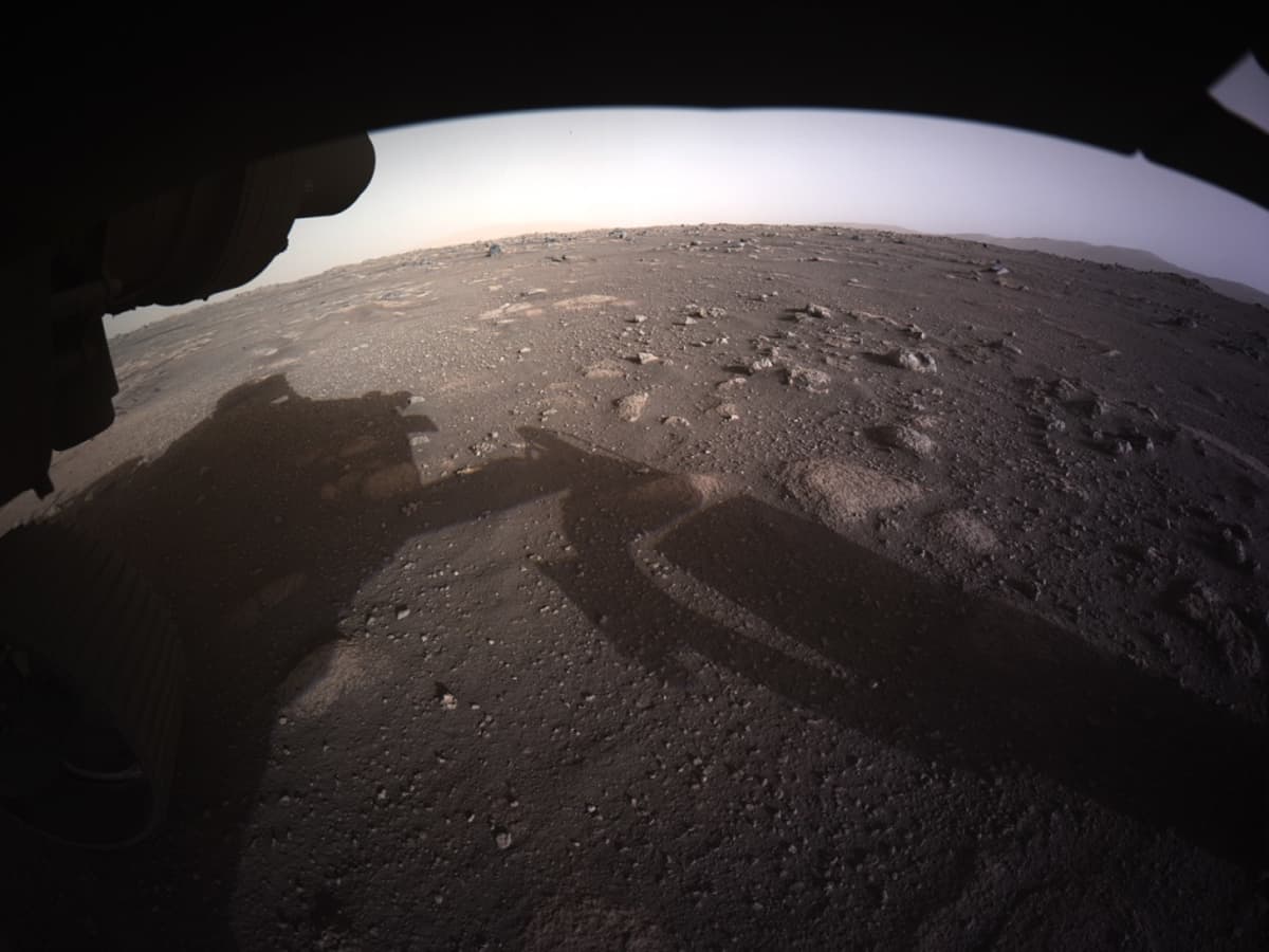 Marsin punainen pinta, jolle heijastuu mönkijä ja sen robottivarsi. 
