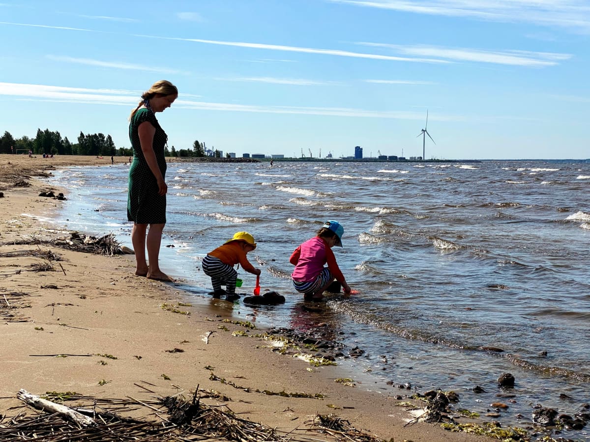Lapsia leikkimässä rantavedessä aikuisen valvoessa Oulun Nallikarissa.