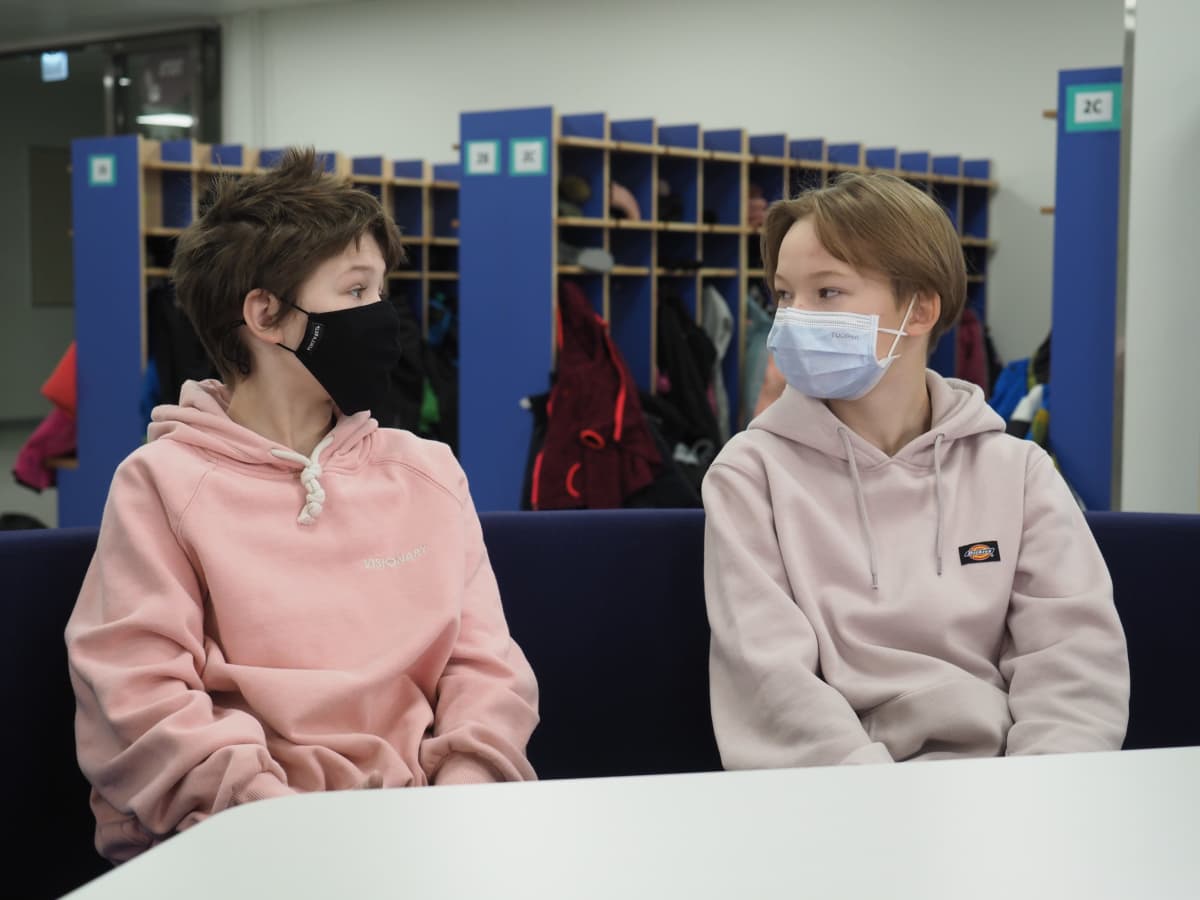 Koulupojat maskit naamallaan koulun aulassa