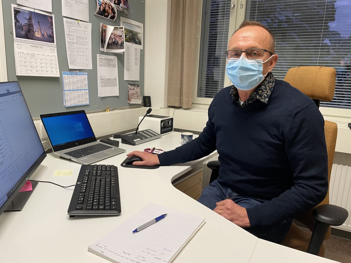 Haukiputaan yhtenäiskoulun rehtori Ari Isomaa istuu työpöytänsä ääressä kirurginen maski kasvoillaan.