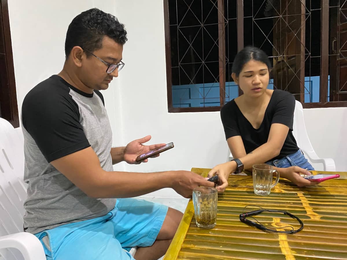 Kansanedustaja Sithu Maung ja hänen sisarensa Wyethee Maung katselevat puhelimiaan pöydän äärellä. 