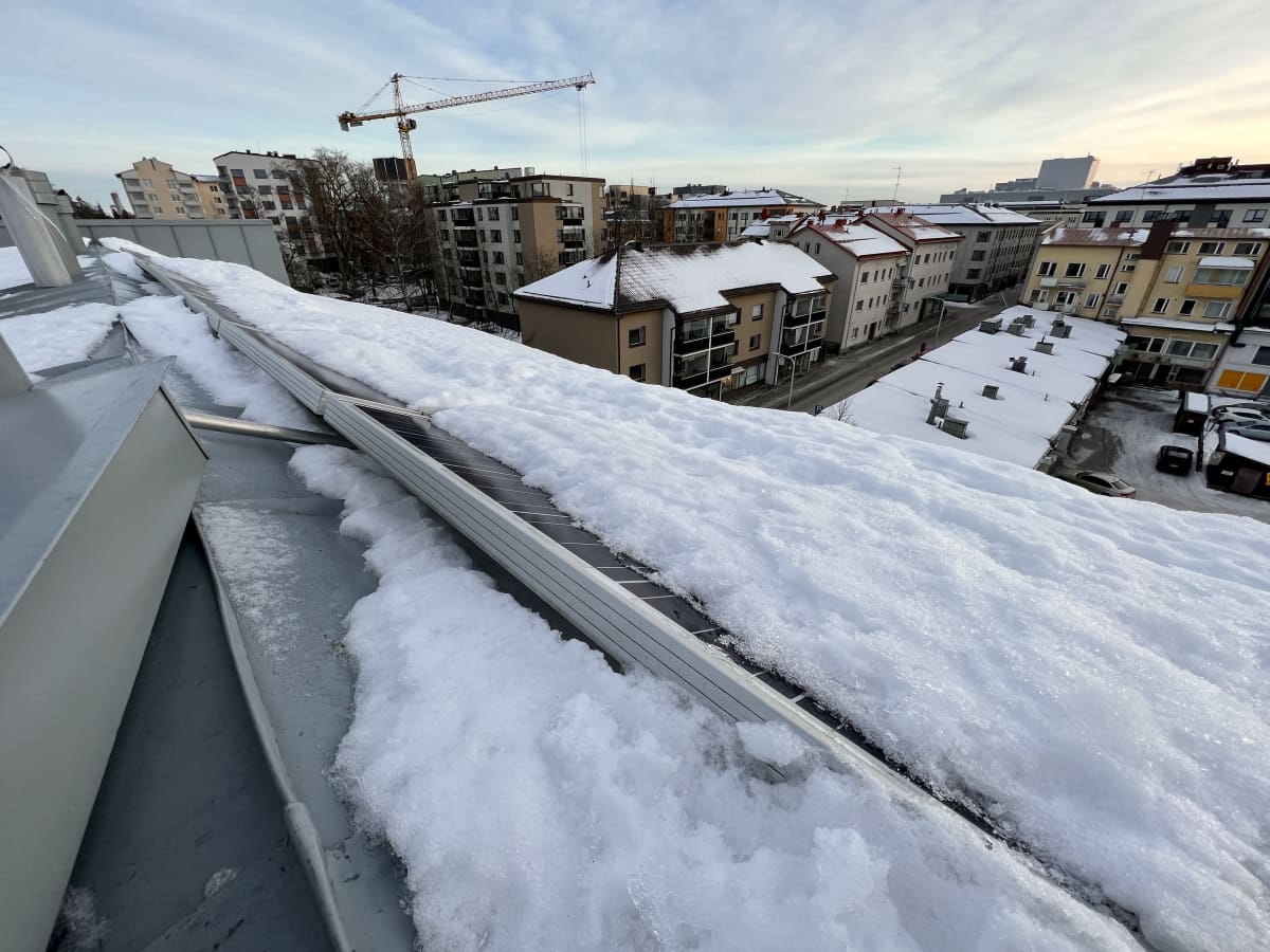 Aurinkopaneeleja lumen peitossa Lappeenrannan keskustassa sijatsevan kerrostalon katolla.