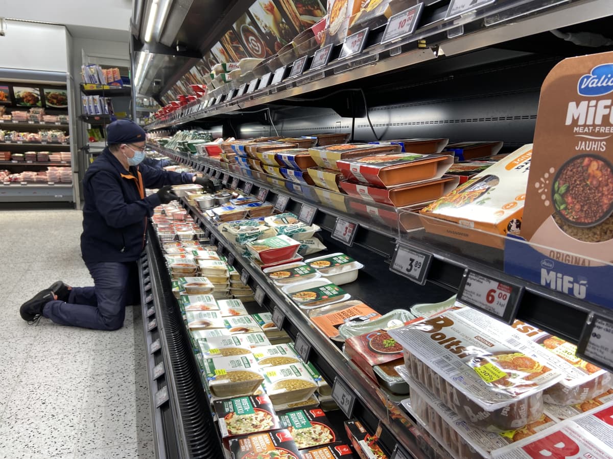 Oriveden K-Supermarketissa lihamestari Jari Pohjonen järjestelee polvillaan hyllyn edessä seisoen eineksiä hyllylle