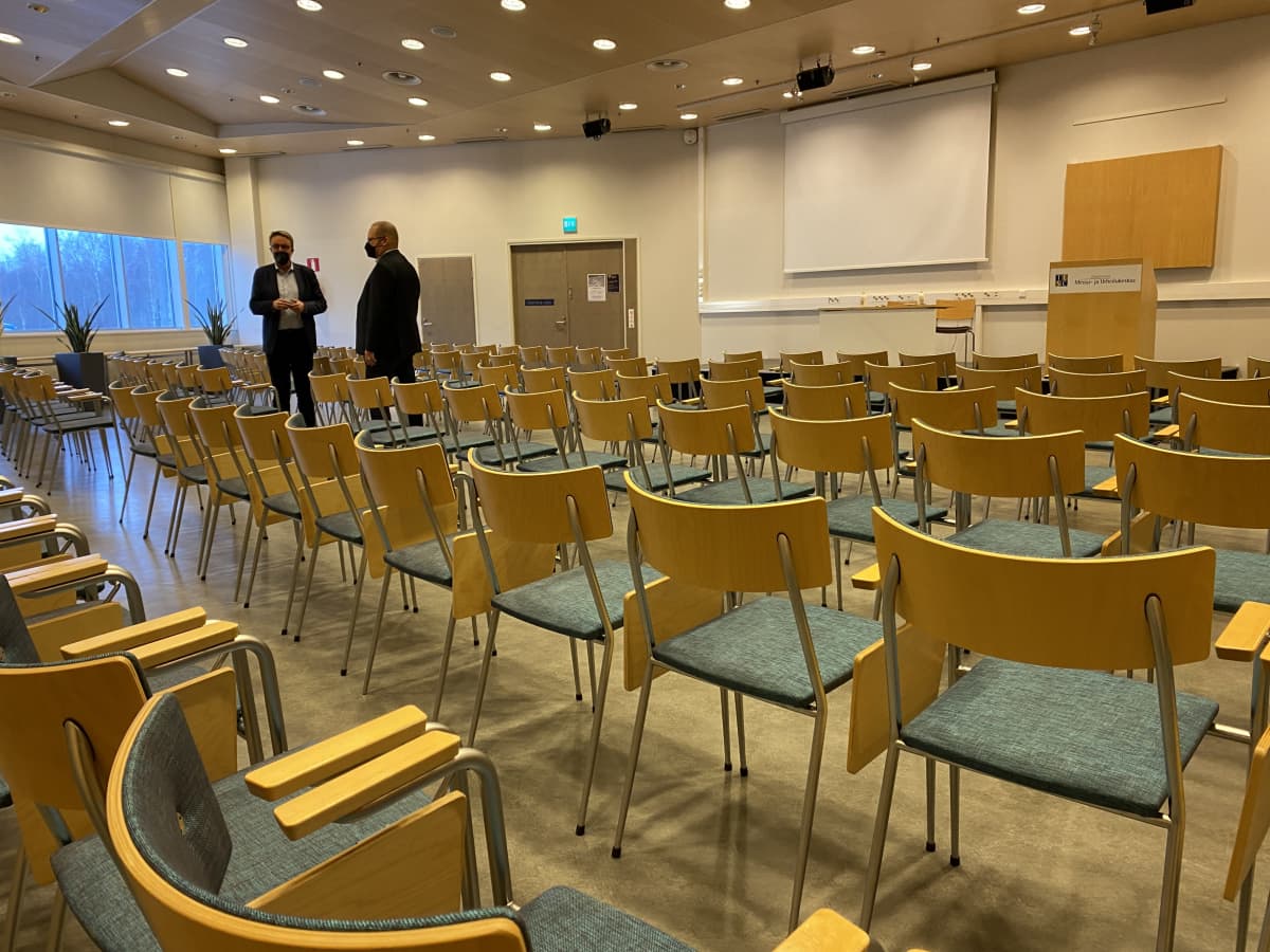 Kaksi miestä isossa salissa, paljon tyhjiä tuoleja. Tähtisali Tampereen Messu- ja urheilukeskuksessa. 