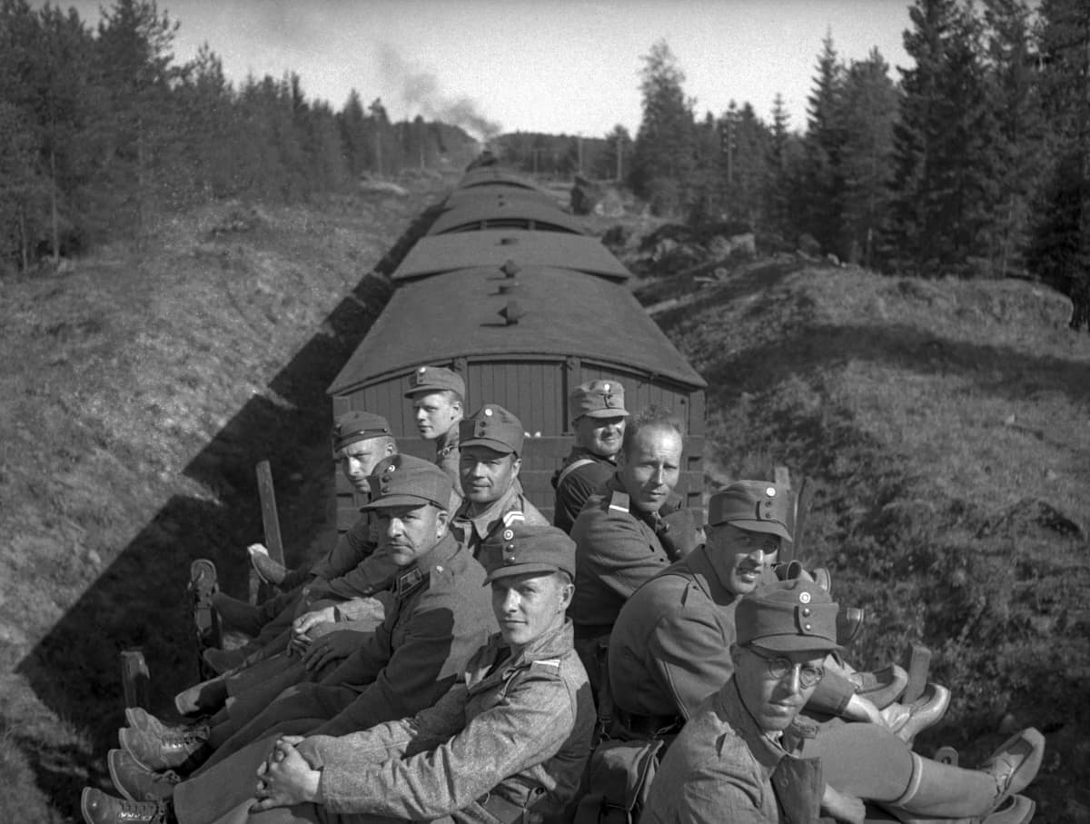 9 sotilasta istuu selät vastakkain junan katolla matkalla sotaan.