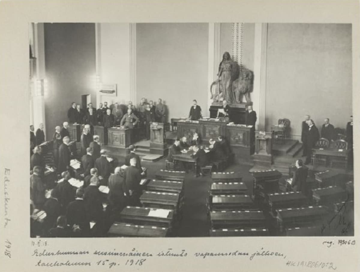 Mustavalkoinen kuva eduskunnasta, jonka toisen puolikkaan istuimet ovat tyhjä yhtä miestä lukuun ottamatta.