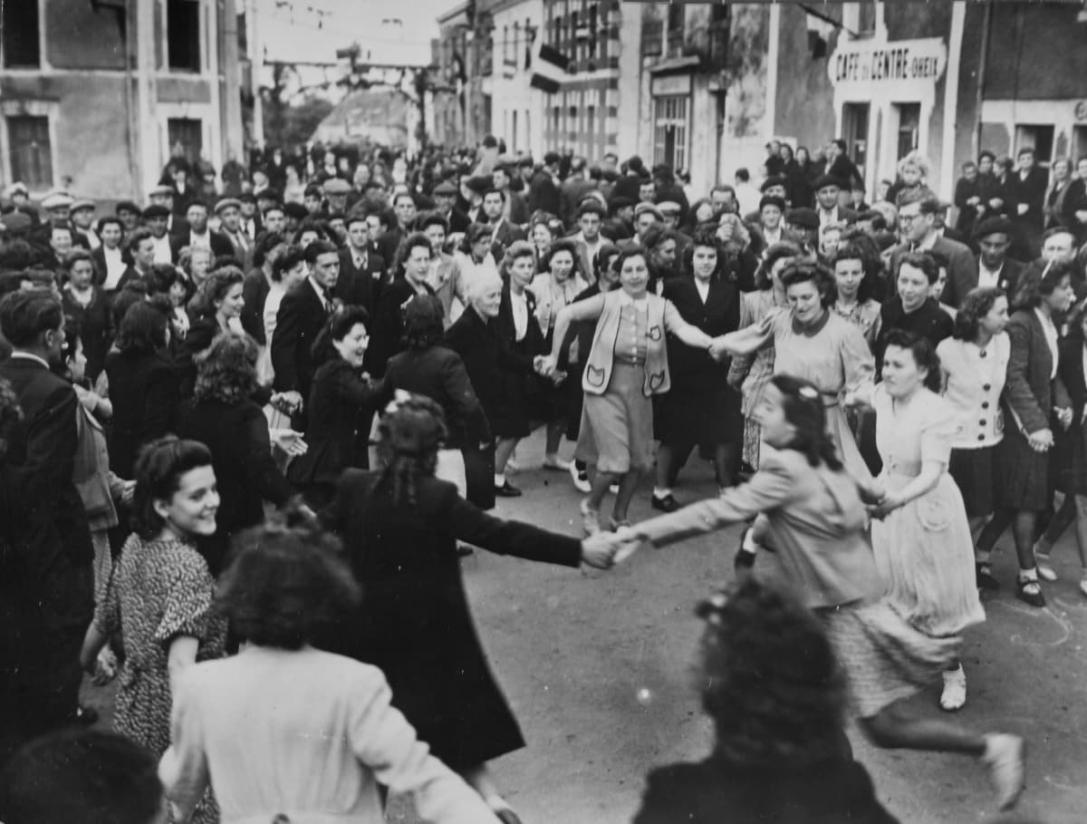 Naiset tanssivat piirissä ihmisjoukon keskellä.