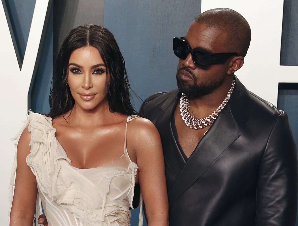 Kim Kardashian vaaleassa iltapuvussa ja Kanye West mustassa nahka-asussa
