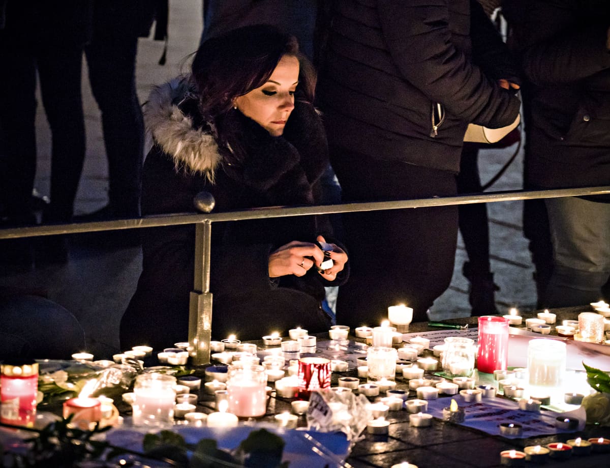 Nuori nainen sytyttämässä kynttilää Strasbourgin keskusaukiolla keskiviikkona 12. joulukuuta.