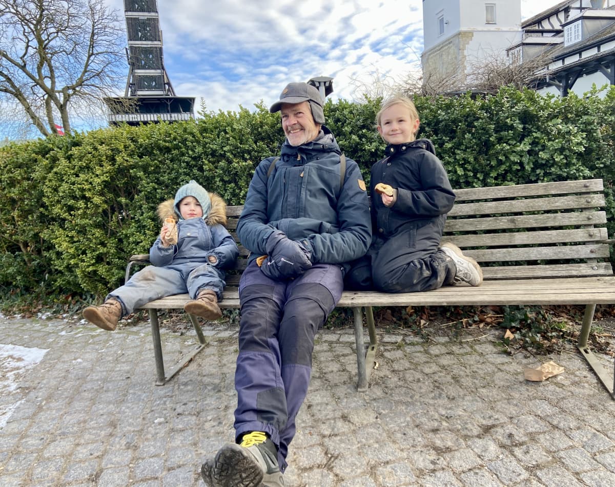 Isoisä puistonpenkillä lastenlastensa kanssa.