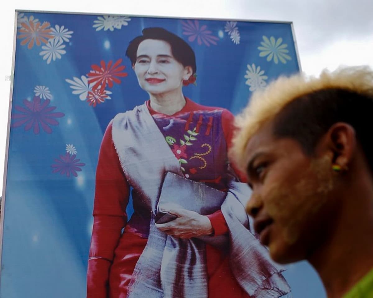 Nuori mies ohittaa vaalijulisteen, jossa on perinneasuisen Aung San Suun kuva. 
