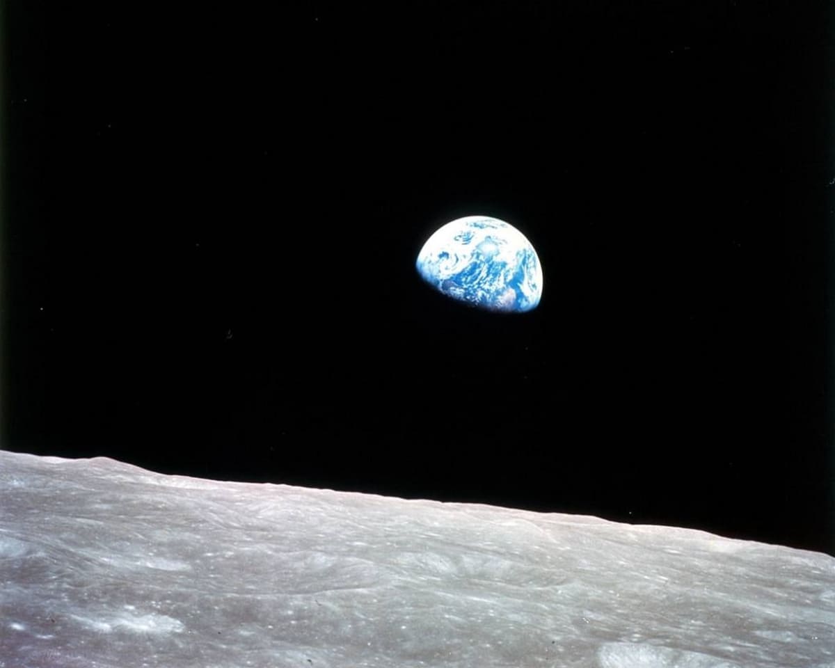 Kuun pintaa ja takana pimeydessä osa sinisestä maapallosta. 