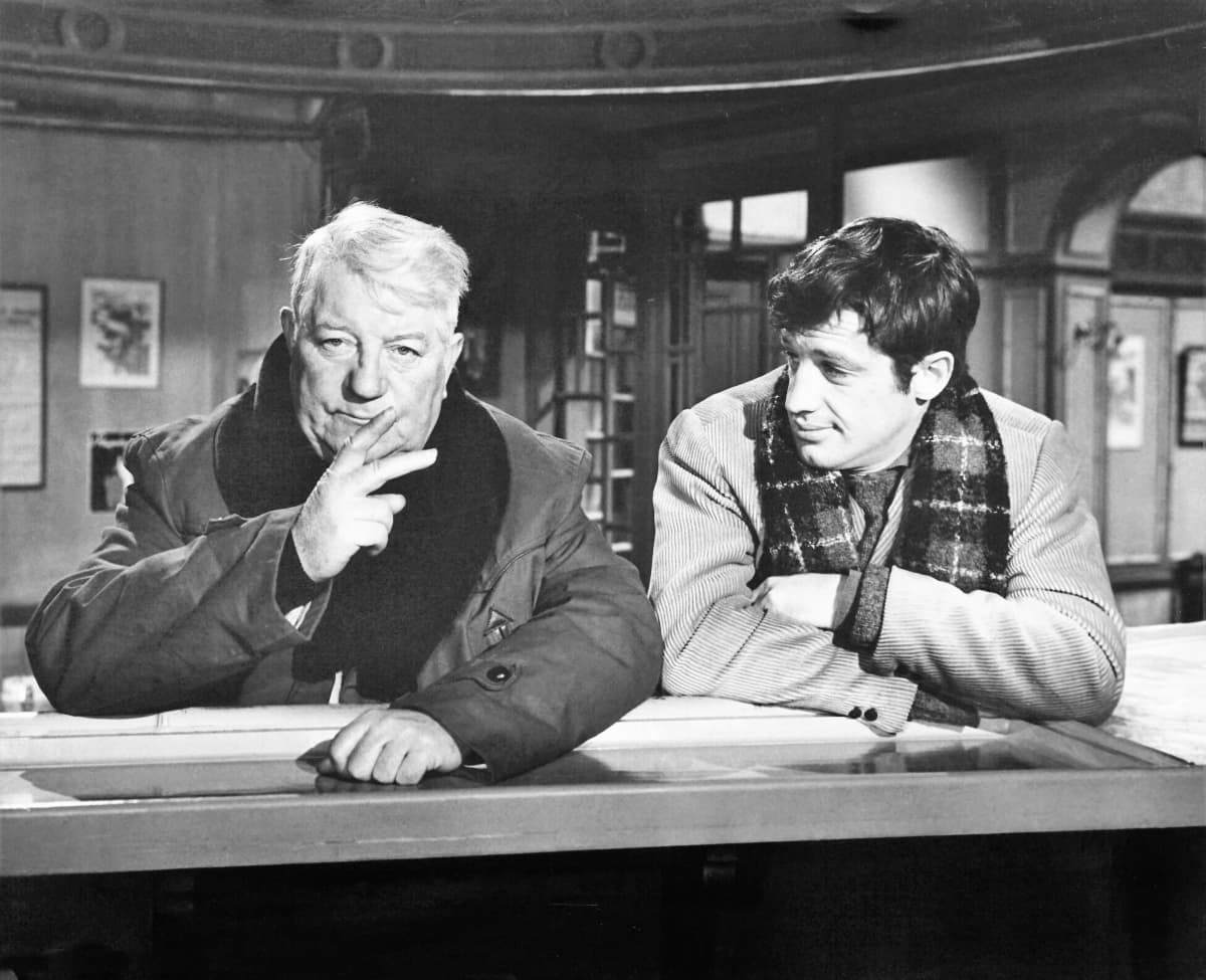 Mustavalkokuvassa vanha Gabin ja nuori Belmondo nojaavat päällystakeissaan kaululiinat kaulassaan baaritiskiin, ja Gabin näyttää sormillaan tilausta, kaksi annosta.