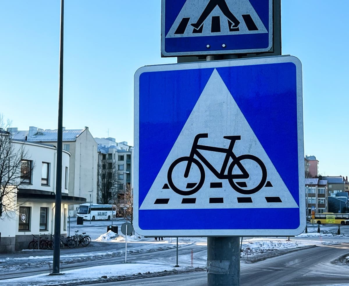 Liikennemerkki B7, väistämisvelvollisuus pyöräilijän tienylityspaikassa. Neliönmallisessa sinipohjaisessa merkissa on valkoisen kolmion sisällä polkupyörän kuva sekä katkoviivoitus osoittamassa pyörätien jatketta.