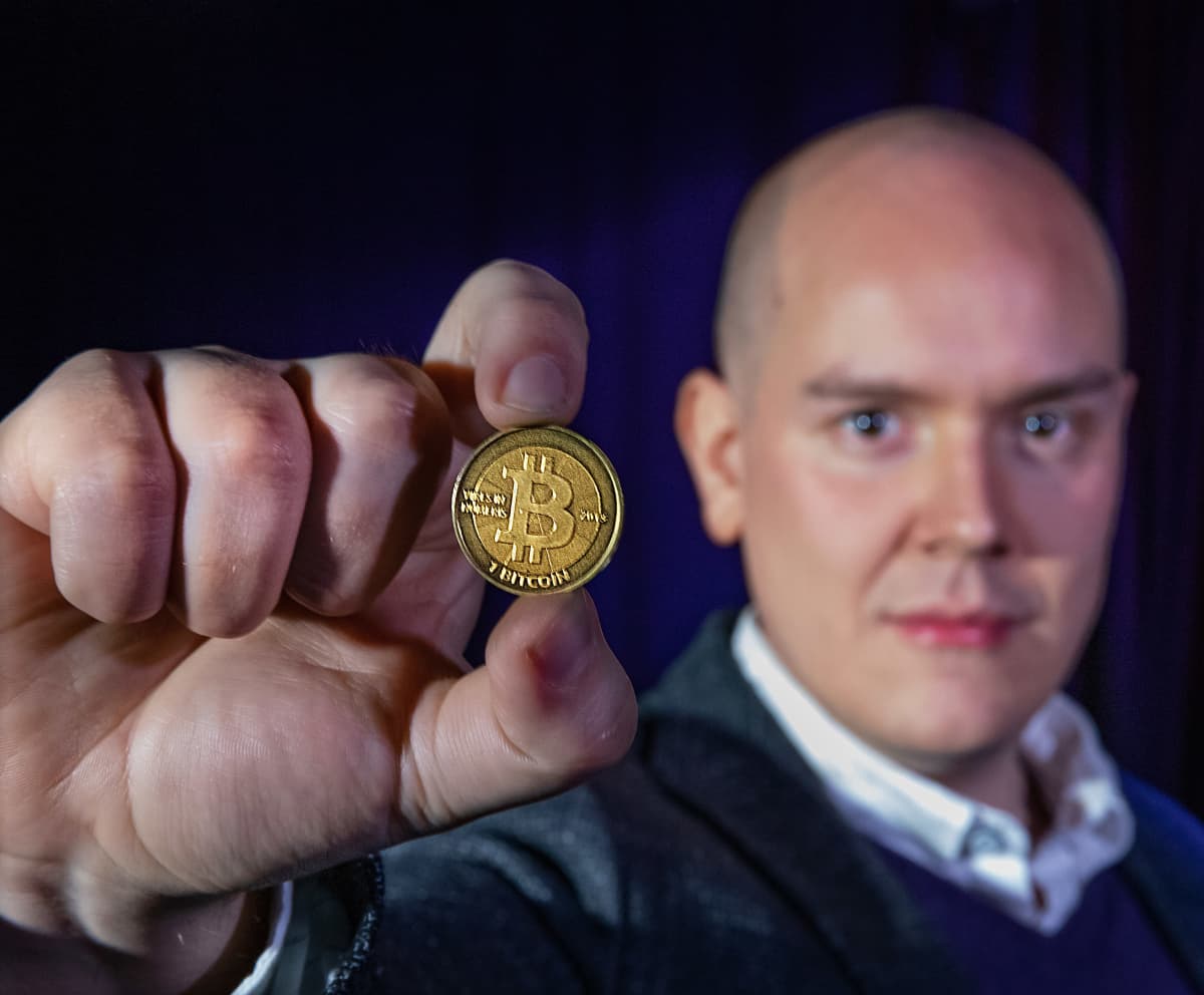 Patrik Elias Johansson kädessään Bitcoin-kolikko.