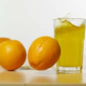 Appelsiineja ja juomalasi pöydällä.