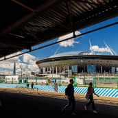 Suuren avaruusaluksen näköinen stadion kuvattuna kesäisenä päivänä läheisen sillan alta.